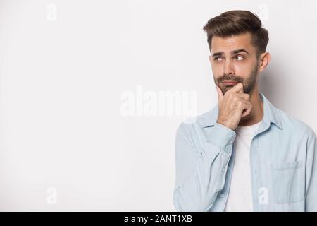 Pensive young guy looking aside at empty copy space. Stock Photo