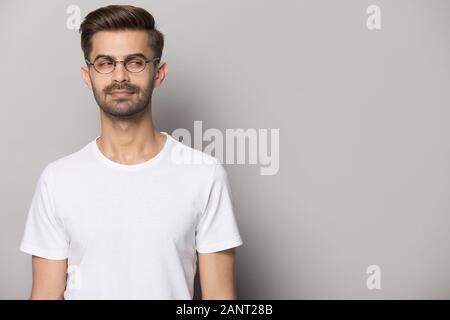 Suspicious young man wearing eyeglasses looking aside on copy space. Stock Photo