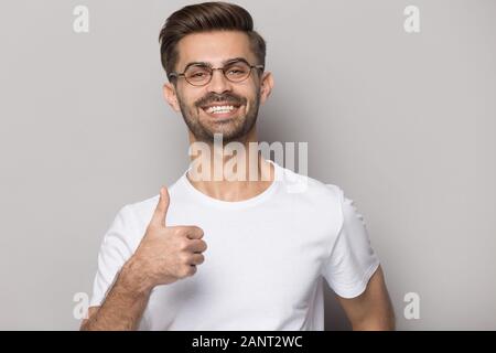 Happy smiling millennial guy in eyewear showing thumbs up gesture. Stock Photo