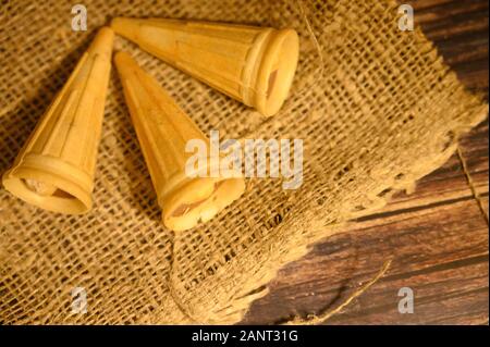 Three cakes in waffle cones on a background of rough homespun fabric. Close up Stock Photo