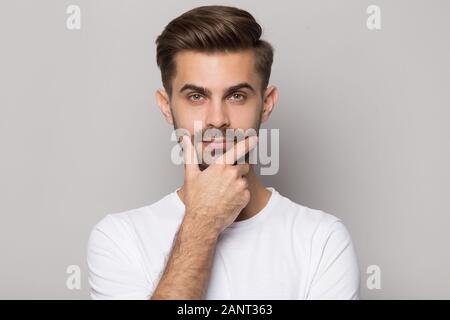 Young thoughtful bearded man touching chin head shot close up. Stock Photo