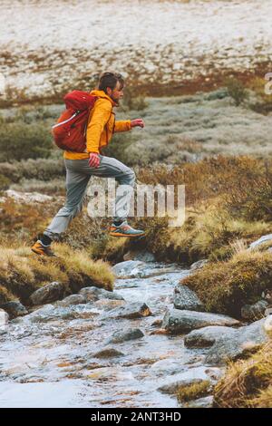 Man trail running crossing river adventure travel vacations hiking active healthy lifestyle outdoor runner with backpack in mountains Norway Stock Photo
