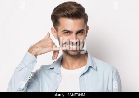 Happy smiling young guy showing call me back gesture. Stock Photo