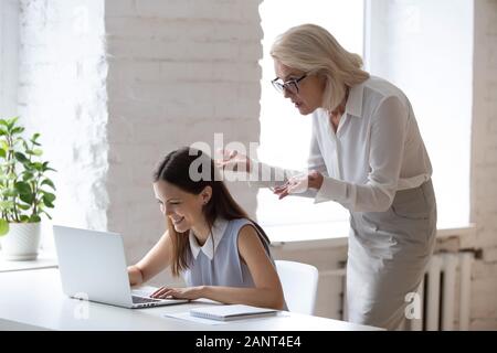 Worker typing on computer angry boss looking at laptop screen Stock Photo