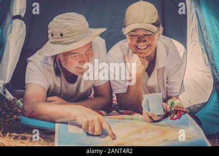 Happy senior traveler people together looking a paper map to choose the next holiday vacation travel destination - wanderlust no age limit lifestyle c Stock Photo