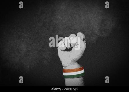 26 January, India national flag on a wrist of male clenched fist. Strength, Power, Protest, unity concept. Grain texture with black and white effect, Stock Photo