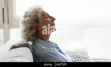 Head shot profile peaceful older woman relaxing on couch