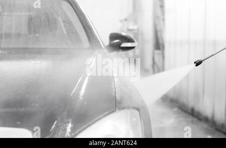 Car washing service. Worker cleaning auto using high pressure water Stock Photo
