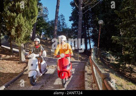 Happy young man and girl  riding a scooter and having fun. Stock Photo