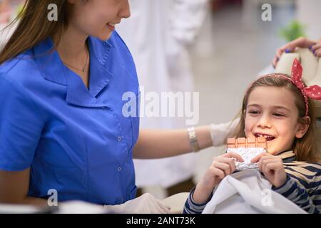 Cute little girl at dentist’s office holding a chocolate Stock Photo