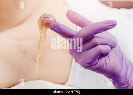 Woman underarm shugaring paste hair removal procedure beauty salon. Epilation concept Stock Photo