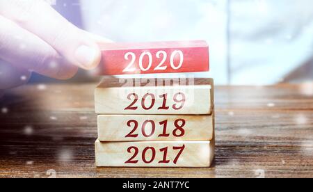 Businessman builds wooden blocks 2020. The concept of the beginning of the new year. New goals. Next decade. Trends and changes in the world. Build pl Stock Photo