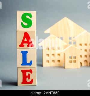 Wooden blocks with the word Sale and wooden miniature houses. The concept of the sell of real estate, apartments and residential premises. Rent and mo Stock Photo