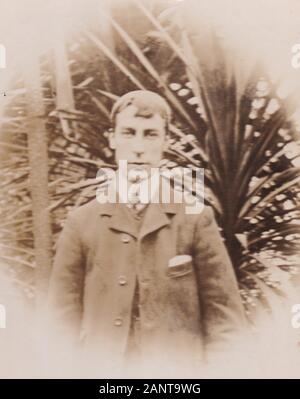 Vintage black and white 1900s photo of a young man wearing a suit with big collared shirt and overcoat. Stock Photo
