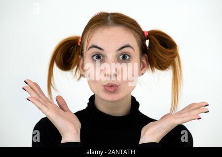 Closeup portrait of a funny redhead teenage girl with childish hairstyle isolated on white backround. Stock Photo