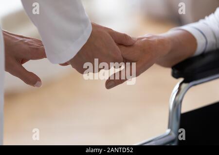 Close up caregiver holding disabled older woman hand Stock Photo