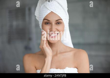 Head shot beautiful woman wearing towel cleaning skin with sponge Stock Photo