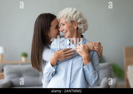 Happy grandmother and granddaughter touching noses, hugging at home Stock Photo