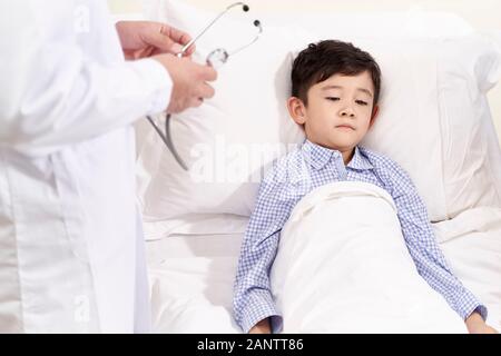 five year old child lying in bed in hospital ward looking sad and depressed Stock Photo