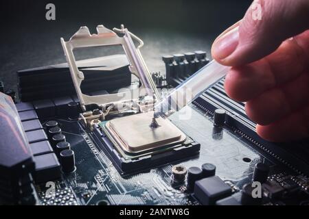 Close up to technician squeezing or application the thermal paste compound on the top of main cpu in the socket. Concept of repairing or upgrading Stock Photo
