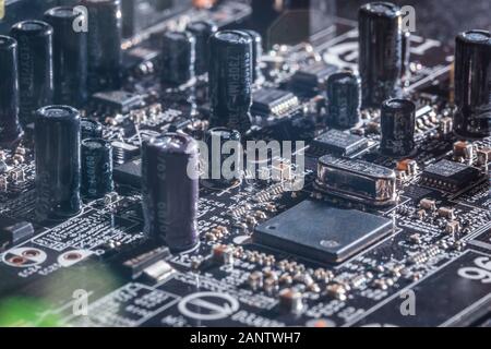 Photo of electric component in electronic device, contain black microchip as main object, black capacitors and resistors on black printed circuit Stock Photo