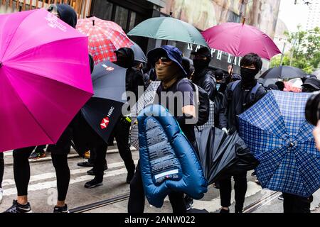 Protesters shield themselves with umbrellas during the rally.Entering the 8th month of civil unrest, protesters gathered at an anti-communist rally, protesting against the Chinese Communist Party. Demonstrators listened to speeches, waved flags, and chanted slogans. Later, police in riot gear appeared and fired tear gas, arresting several protesters. Stock Photo