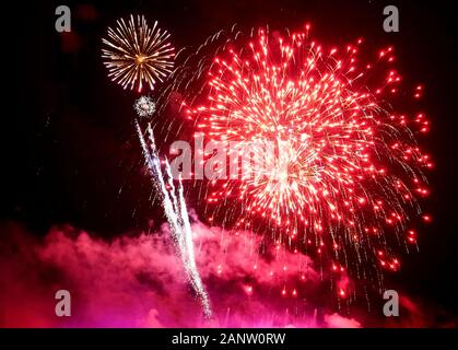Stunning red fireworks balls exploding on the sky at night Stock Photo