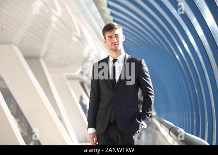 Portrait of happy young businessman standing on office corridor looking at camera Stock Photo