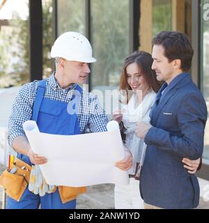 Foreman showing house design construction plan to a happy young couple new house real estate concept Stock Photo