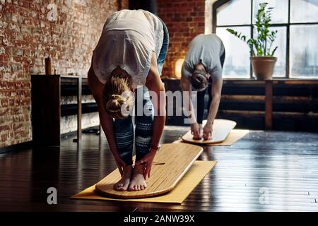 Group of young sporty people, man and woman practicing yoga lesson with instructor, working out, indoor close up image, studio on yoga board Stock Photo