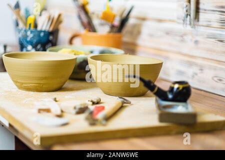 Plates and tools on pottery studio table, shallow debt of field, small art business concept Stock Photo
