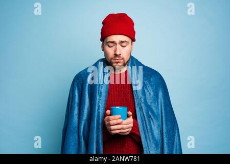 Boy caught a cold and drinks hot the. Cyan background. Concept of illness Stock Photo