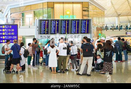 Hong Kong: A group of chinese tourists with a tour guide in front of the information board inside Hong Kong International Airport Stock Photo