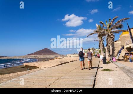 EL MEDANO, SPAIN - JULY 7 2019: People walking on promenade and surfing, kiting and windsurfing in Granadilla de Abona municipality Stock Photo
