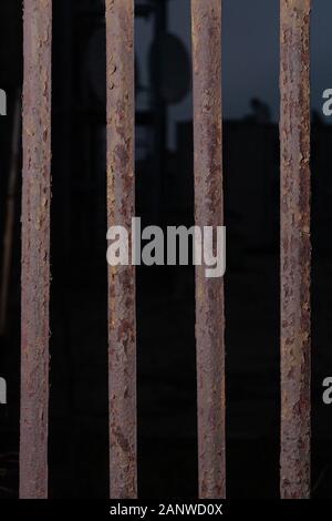 Old abandoned and rusty mesh fence. Stock photo close-up of a rusty fence at night. Stock Photo