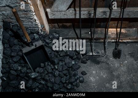 A coal shovel stuck in a pile of coalat the basement prepared for heating the house with. Stock Photo