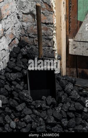 A coal shovel stuck in a pile of coalat the basement prepared for heating the house with. Stock Photo