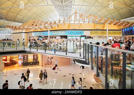 Hong Kong: Tourists at restaurants in the transit area inside Hong Kong International Airport with its futuristic architecture Stock Photo