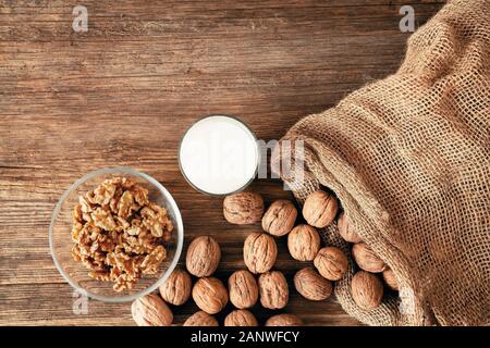 whole walnuts in a cotton bag, scattered nuts on a wooden table. Walnut kernels in a bowl. Stock Photo