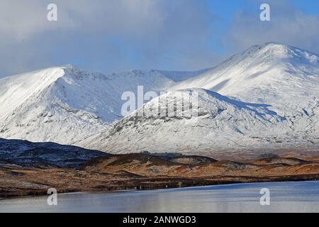 Black Mount mountains in Rannoch Moor, Glencoe, Scottish Highlands in winter with snow. Lochan in foreground. Stock Photo