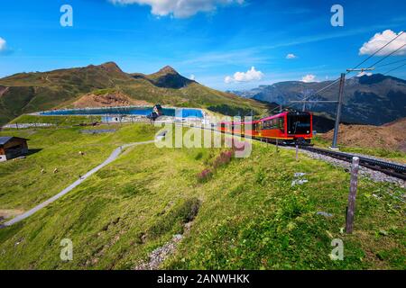 Popular electric red tourist train coming down from the Jungfraujoch station(top of Europe) in Kleine Scheidegg station, Fallbodensee lake, Bernese Ob Stock Photo