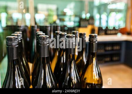 dark amber glass wine bottles top, seal, neck and shoulder close up selective focus view, new bottles with black screw cap on a winery bottling line Stock Photo