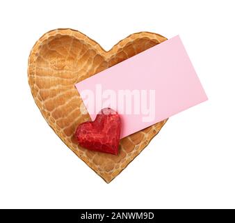 Close up one red painted natural wooden carved heart over pink paper envelope in heart shaped bowl isolated on white background Stock Photo