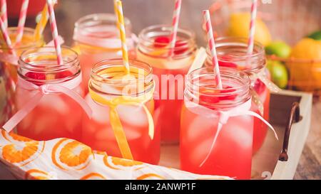 Raspberry lemonade garnished with fresh lemon and raspberries in drinking mason jars. Stock Photo