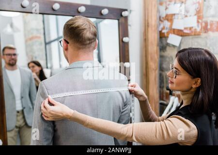Professional tailor working with client in atelier Stock Photo - Alamy