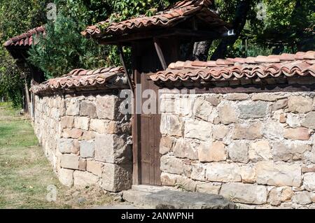 Old rural country house stonewall fence closeup in sunny summer day Stock Photo