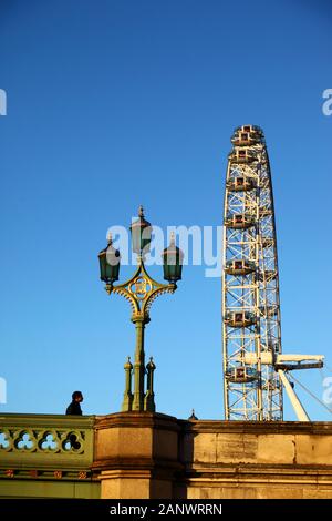Man walking past ornate street lamp on Westminster Bridge and London Eye / Millennium Wheel, London, England Stock Photo