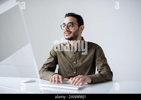 Young confident designer in eyeglasses looking at computer screen Stock Photo