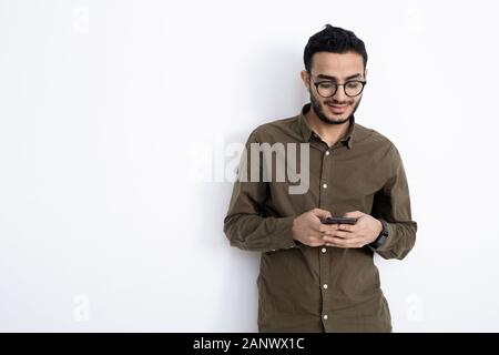 Young smiling businessman in eyeglasses and shirt standing by white wall Stock Photo