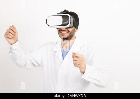 Young smiling male doctor in whitecoat and vr headset standing in isolation Stock Photo